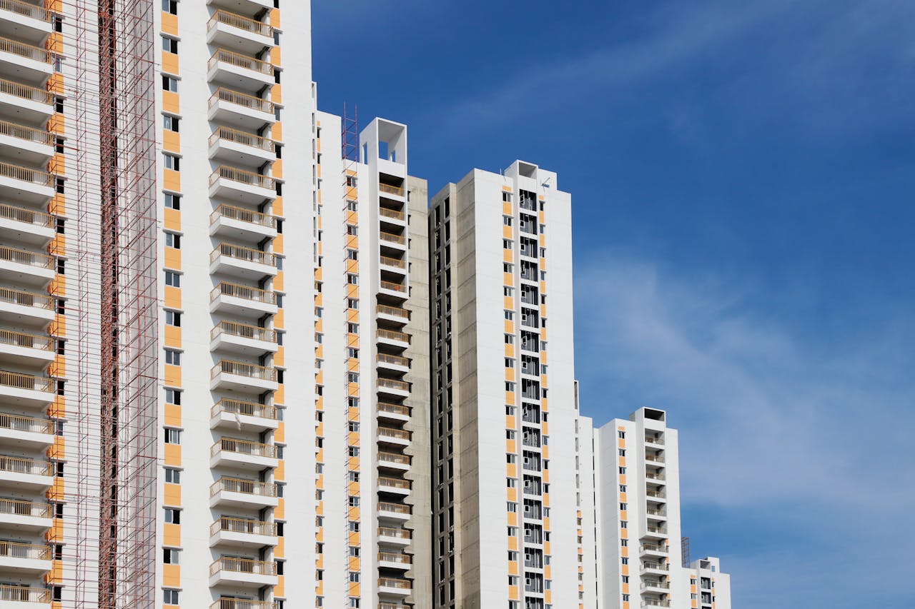 Modern high-rise residential buildings with white facades and blue sky backdrop showcasing urban architecture.